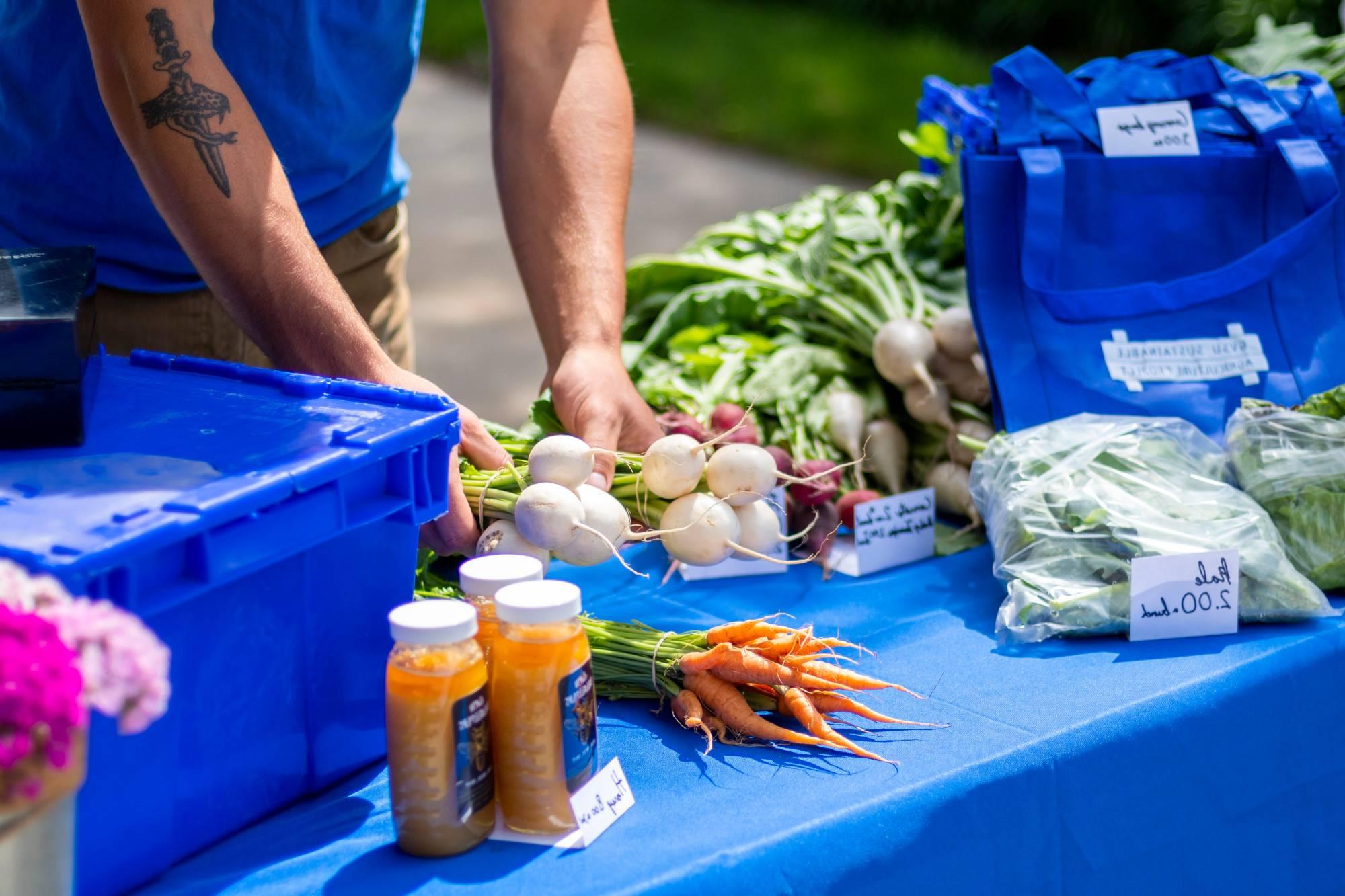 A table at the Farmers Market holding veggies that were grown on the Sustainable Agriculture Project farm at GVSU, and honey from the GVSU Beekeepers Club